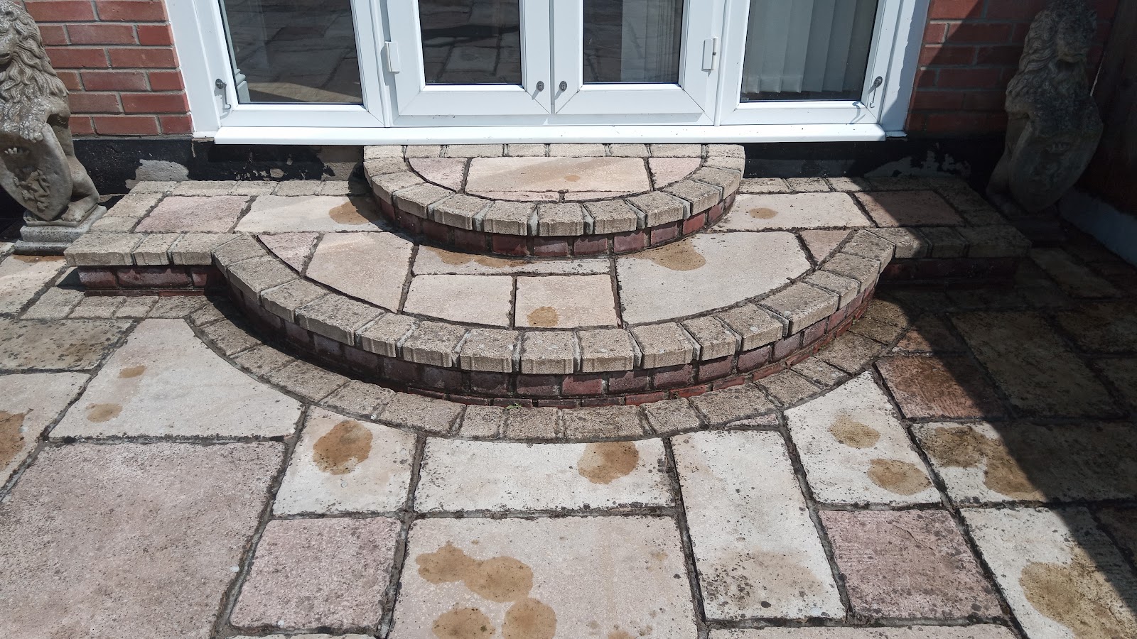 Curved brick steps and circular paving outside french doors