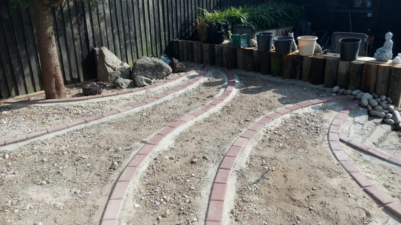 Curved brick-edged paths set out with a sleeper retaining wall