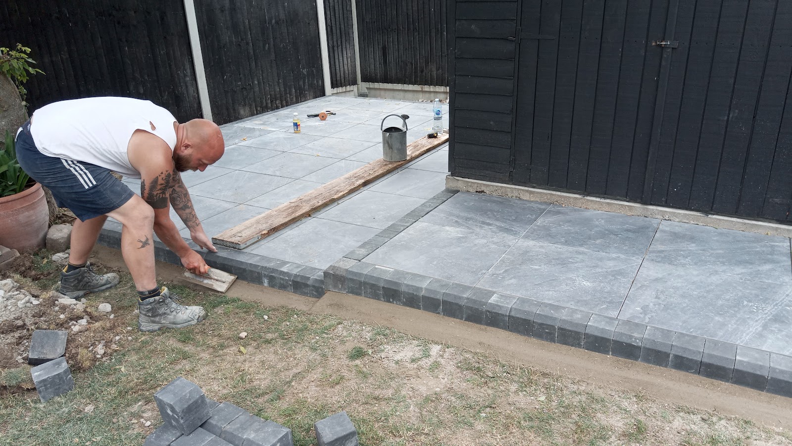 Joe laying charcoal block edging on a porcelain patio