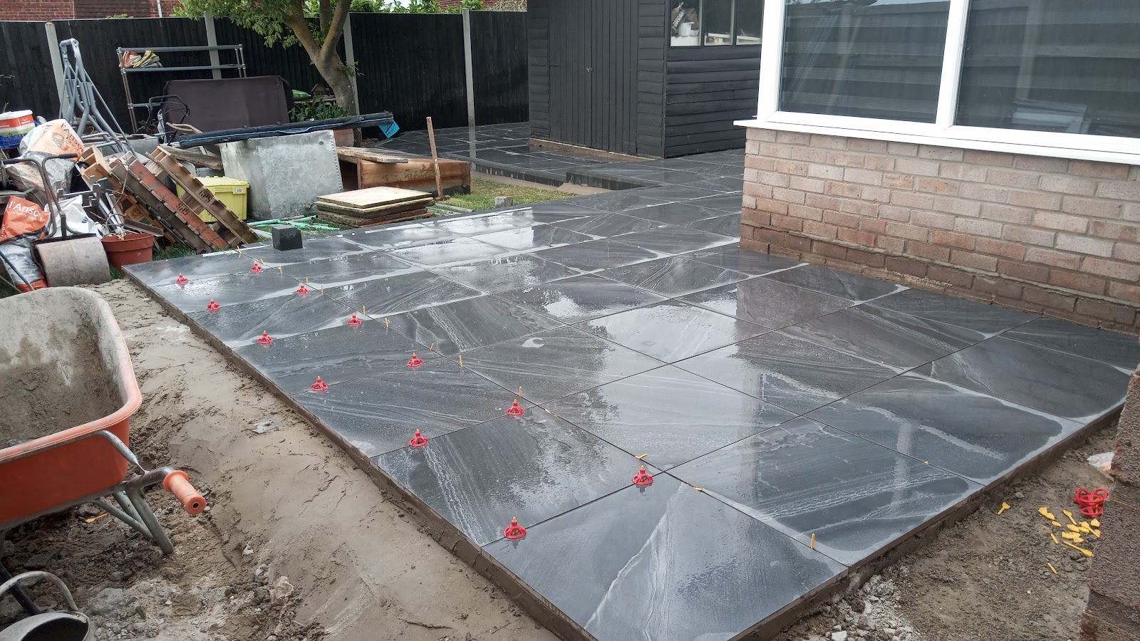Large porcelain patio being levelled beside a brick house