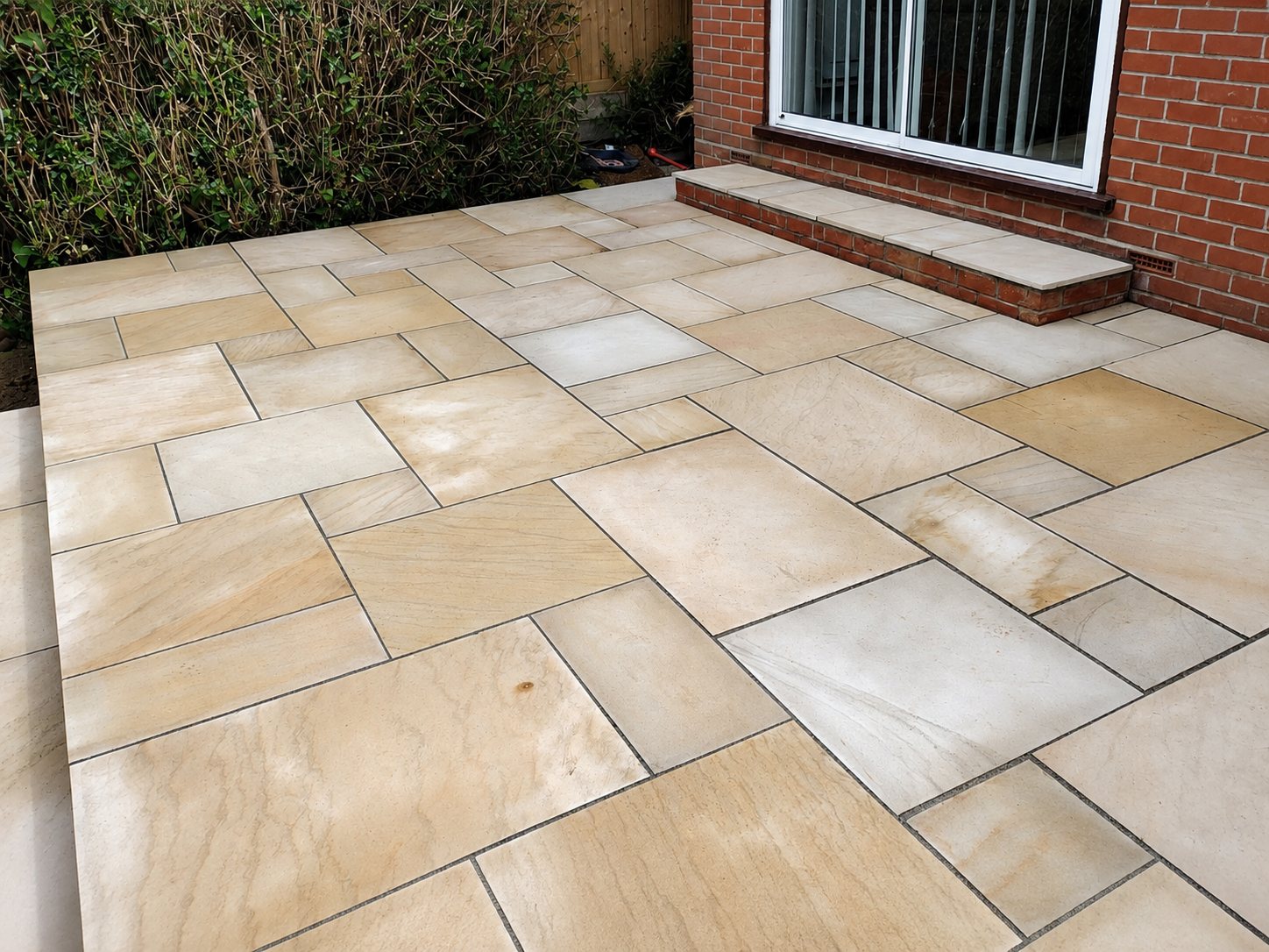 Dark porcelain patio with a strip of new turf